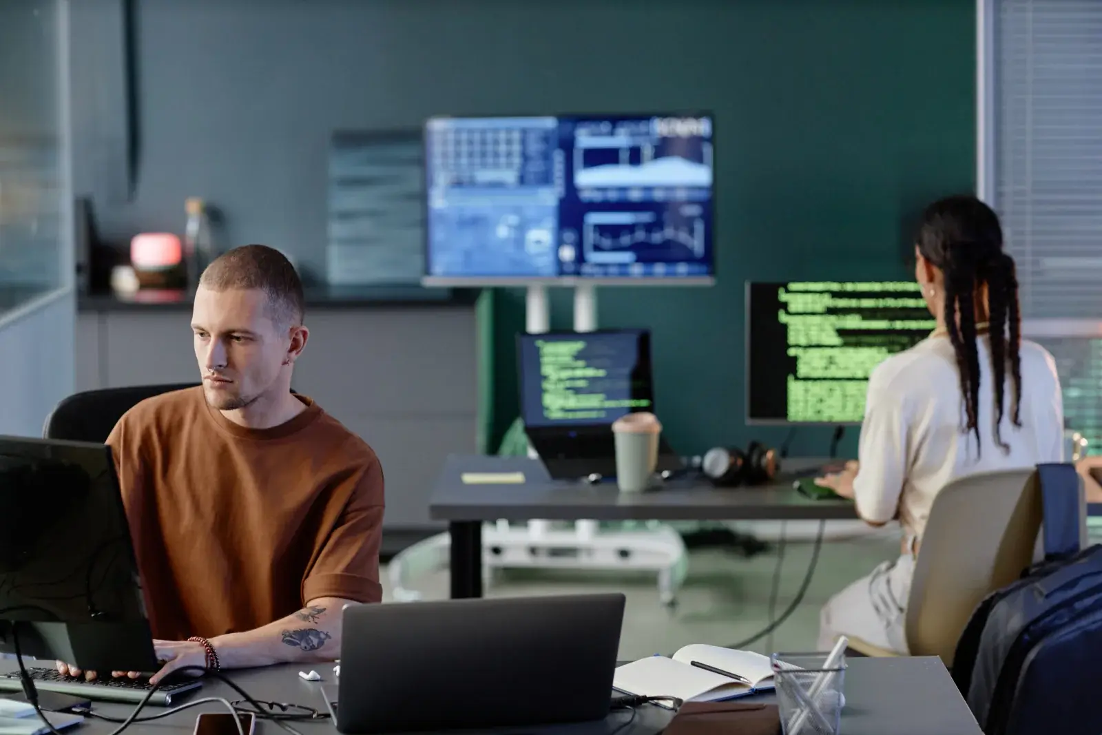 Operations staff using laptops and monitors in a project support room