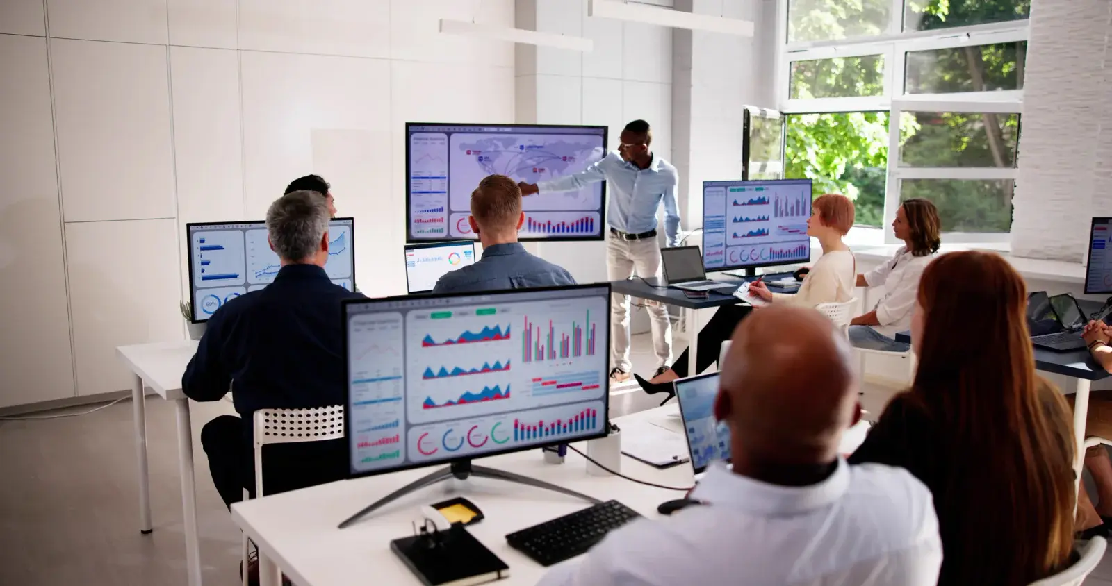 Event planning team monitoring dashboards on laptops and large displays