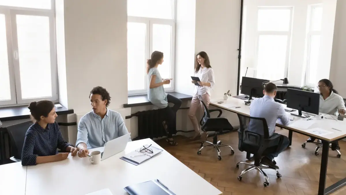 Small team working in a bright shared office with laptops and desktops