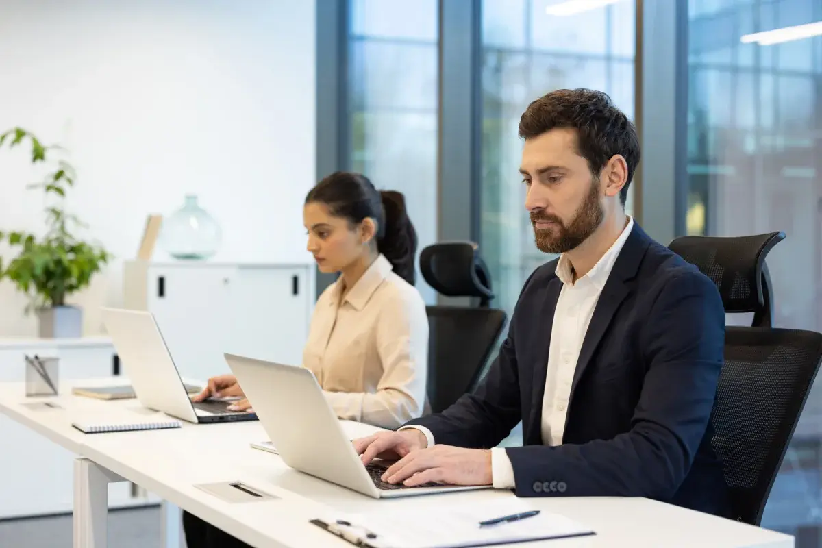 Professionals working on thin Windows laptops in a bright office