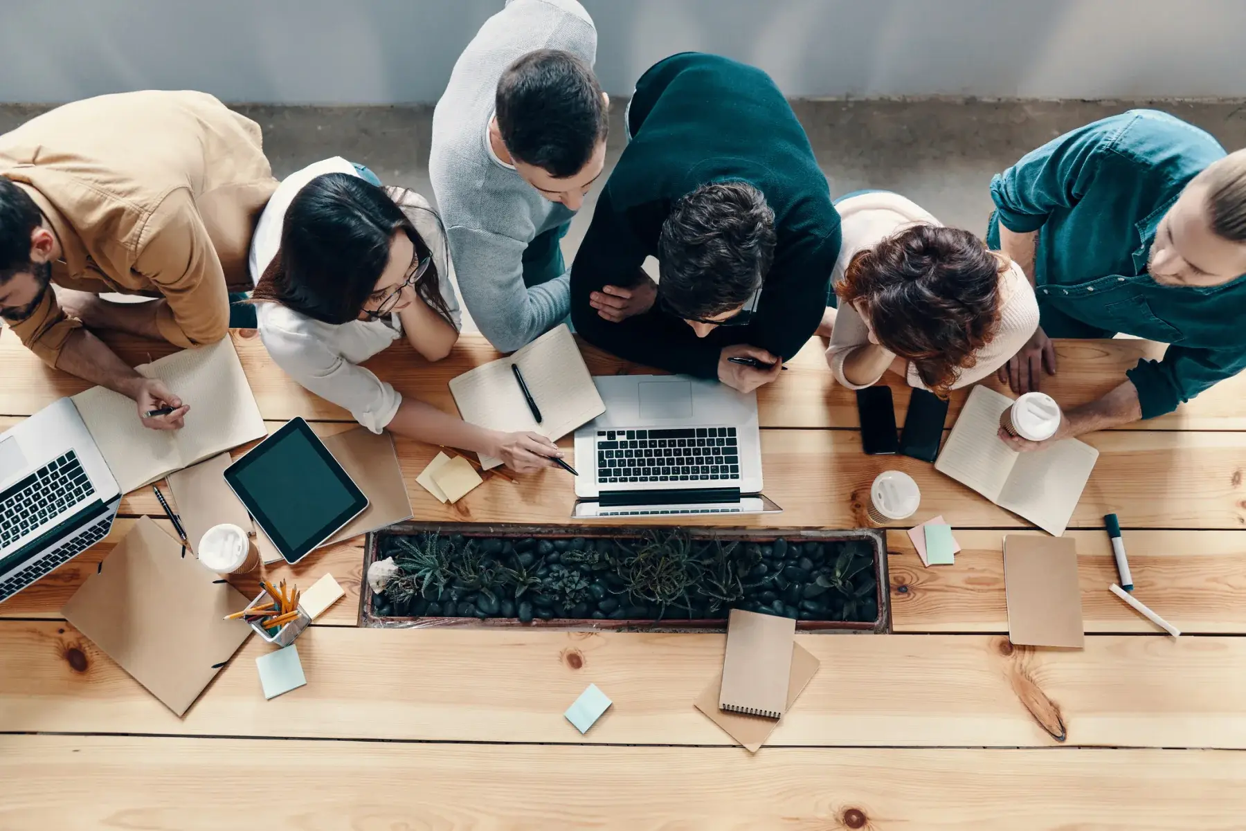 Overhead view of a development team collaborating around laptops