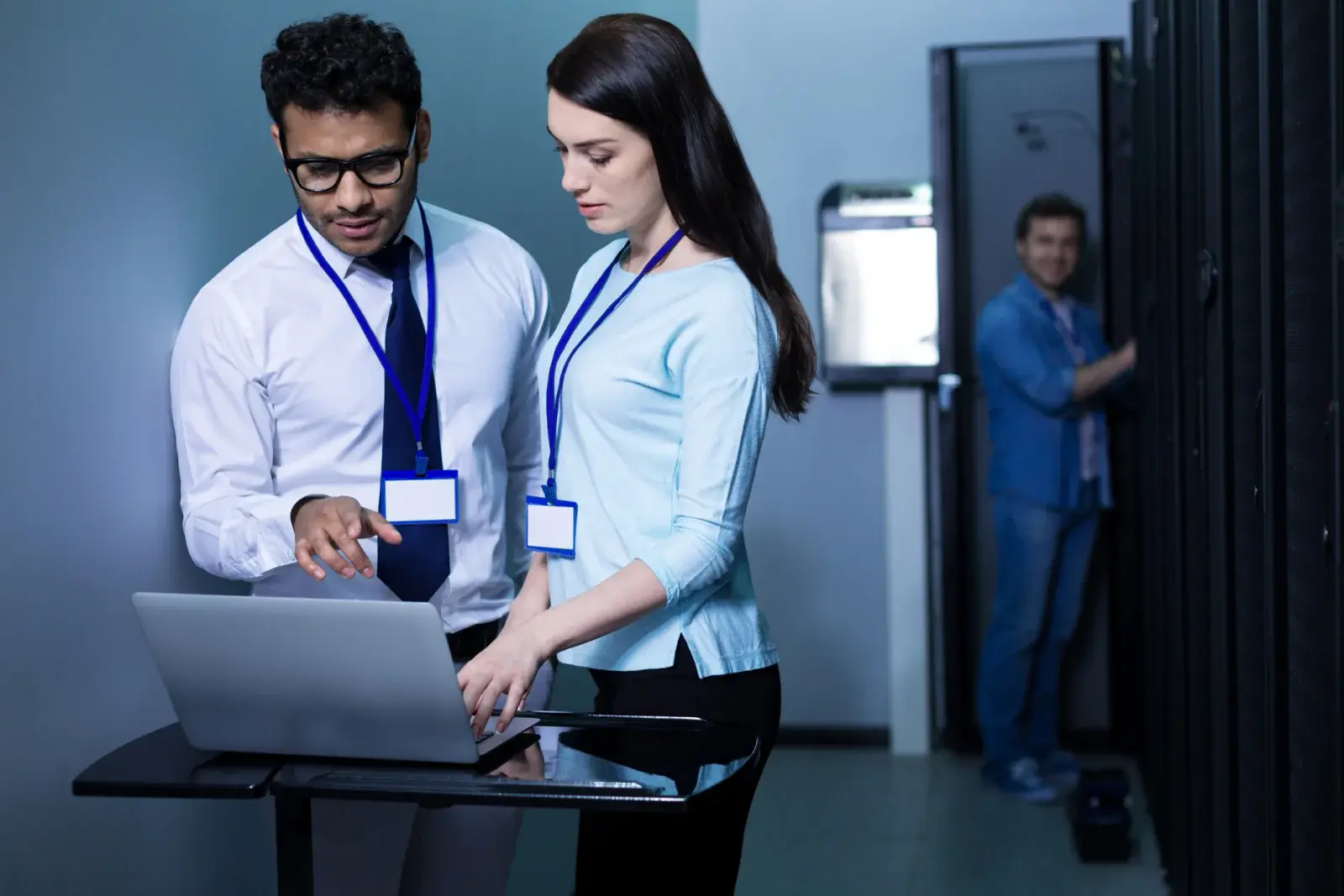 Two IT professionals configuring a laptop in a server room